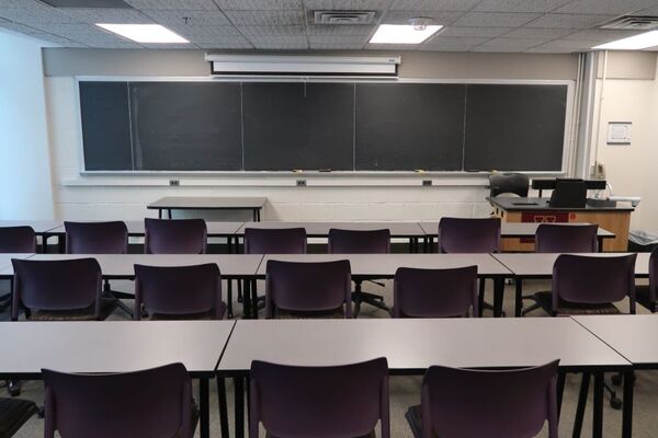 Front of room view with lectern on right in front of chalkboard and projection screen partially raised