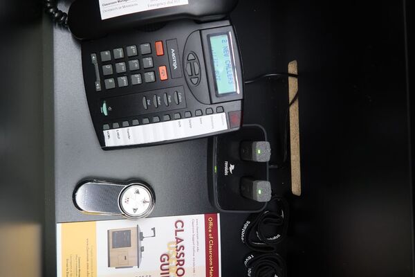 Pedestal - inside view of drawer showing two wireless mics in charging base and telephone