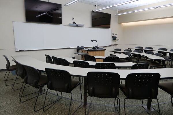 Front of room view with lectern centered in front of markerboard and display monitors above