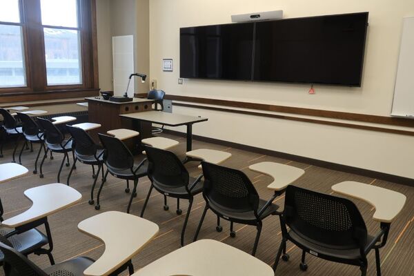 Front of room view with lectern on left in front of display and wall mounted camera