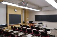 Front of room view with lectern on left side and projection screen partially lowered