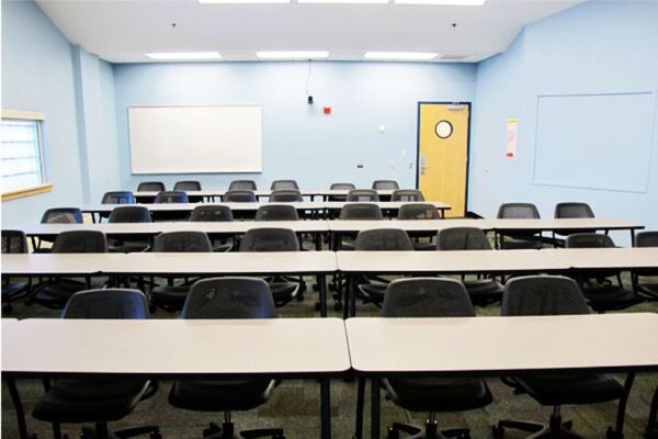 Back of room view of student table and chair seating and exit door at right rear of room