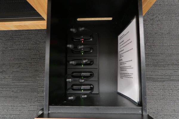 Pedestal - inside view of drawer showing assisstive listening devices in charging base