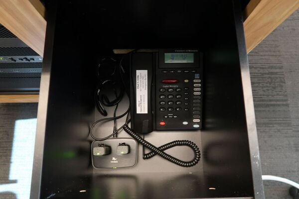 Pedestal - inside view of drawer showing two wireless mics in charging base and telephone