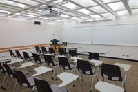 Front of room view with lectern on left and projection screen fully raised