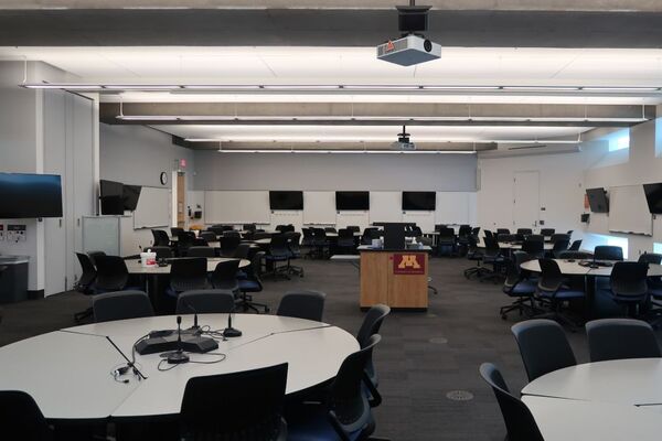 View of student collaborative table and chair seating and exit door at left rear of room