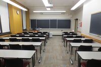 Front of room view with lectern on left side and projection screen partially lowered