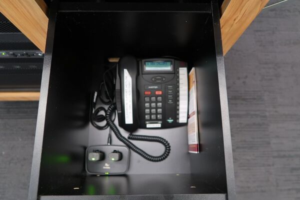 Pedestal - inside view of drawer showing two wireless mics in charging base and telephone