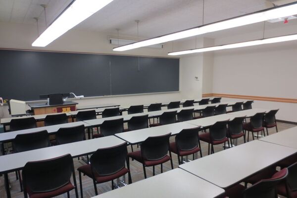 Front of room view with lectern on left side and projection screen partially lowered