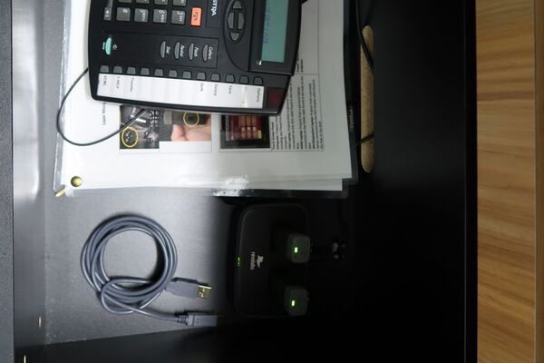 Pedestal - inside view of drawer showing two wireless mics in charging base, telephone, and assistive listening devices in charger