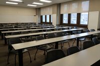 Back of room view of student table and chair seating and markerboard on rear wall