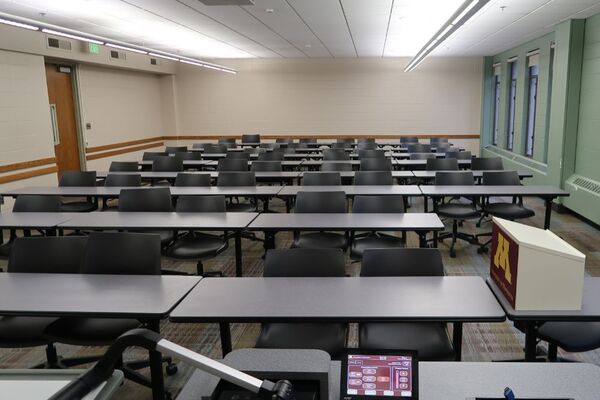 Back of room view of student table and chair seating, exit doors on left wall