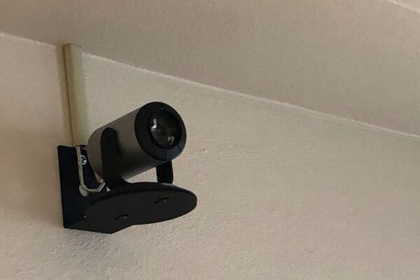 Camera mounted to a wall and instructor enabled adjustments to the lens to allow the instructor to be "seen" by the camera in more locations around the room