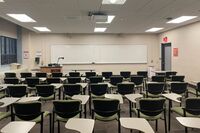 Front of room view with lectern on left in front of markerboard and door on the right