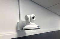 Camera mounted to a wall and instructor enabled adjustments to the lens to allow the instructor to be "seen" by the camera in more locations around the room