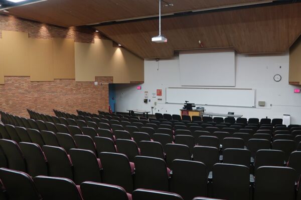 Front of room view with lectern center in front of markerboard and projection screen lowered