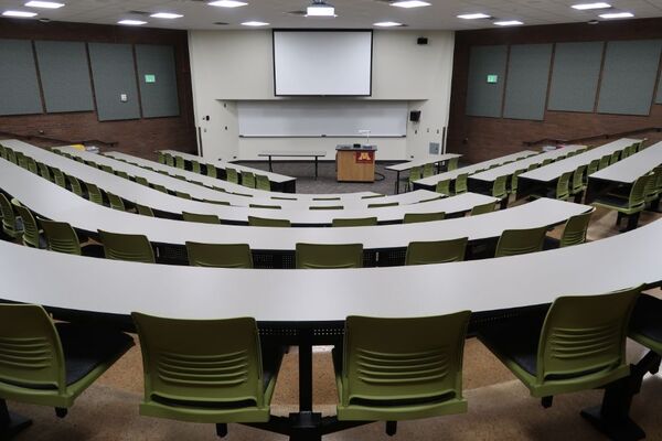 Front of room view with lectern in center of room and projection screen fully lowered