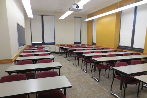 Rear of room view of student table and chair seating with chalkboard at left of room