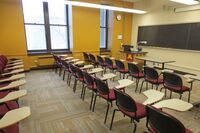 Front of room view with lectern on left side and projection screen partially lowered