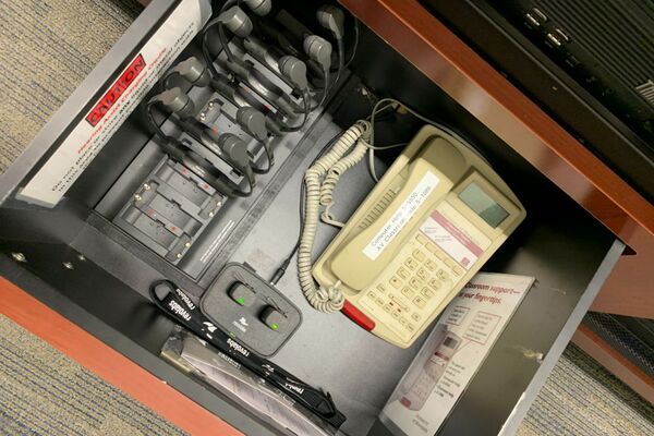 Pedestal - inside view of drawer showing two wireless mics in charging base and telephone