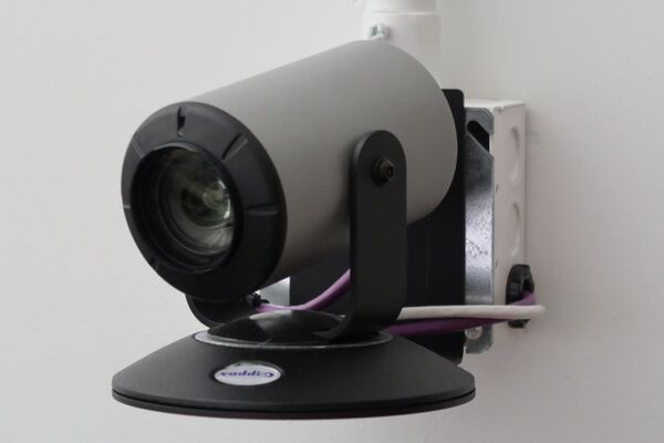 Camera mounted to a wall and instructor enabled adjustments to the lens to allow the instructor to be "seen" by the camera in more locations around the room