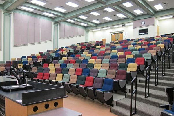 Back of room view of student auditorium seating and control room booth and double exit doors on left