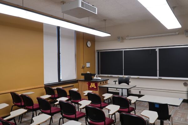 Front of room view with lectern on left side and projection screen fully raised