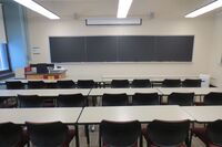 Front of room view with lectern on left side and projection screen partially lowered