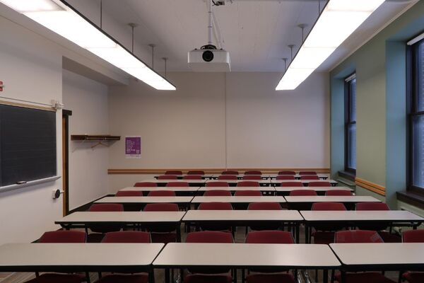 Rear of room view of student table and chair seating with chalkboard at left of room