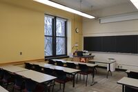 Front of room view with lectern on left side and projection screen partially lowered