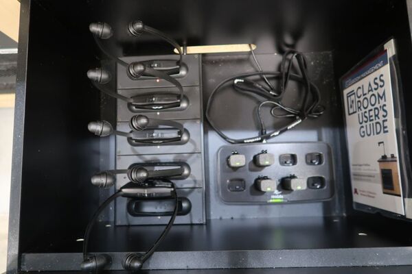 Pedestal - inside view of drawer showing wireless mics in charging base and assistive listening devices in charger