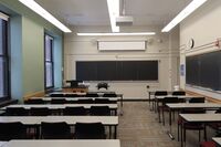 Front of room view with lectern on left in front of room and projection screen partially lowered