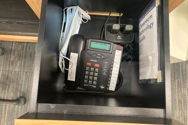 Pedestal - inside view of drawer showing two wireless mics in charging base and telephone