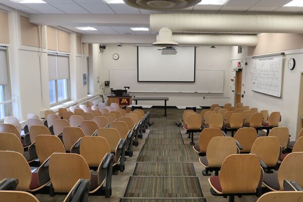 Front of room view with lectern on left side and projection screen fully lowered