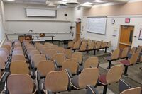 Front of room view with lectern on left side and projection screen partially lowered